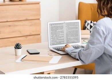 Person arbetar med text på en laptop vid ett skrivbord
